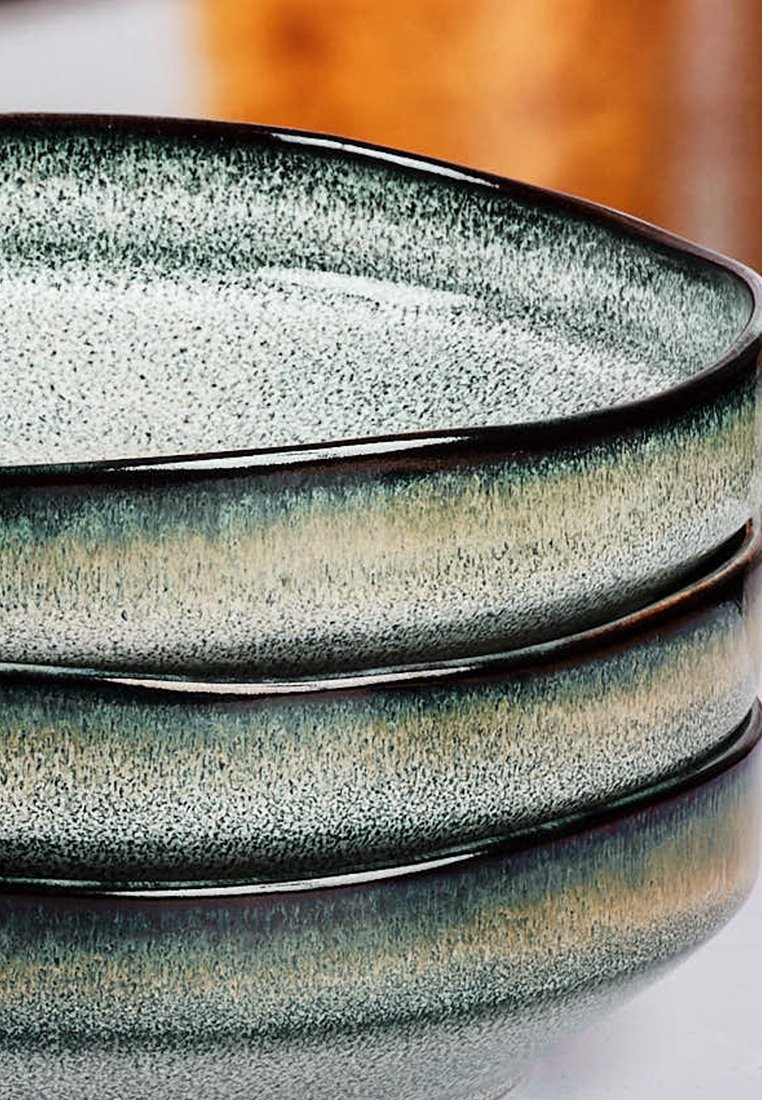 Stapel von drei Keramikschalen mit einer gesprenkelten, hellgrauen Oberfläche und dunklem Rand, die an den Seiten einen Farbverlauf von dunkelgrün zu hellgrün aufweisen.