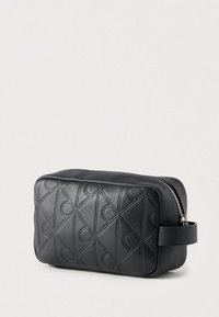 Μαύρη τσάντα από συνθετικό δέρμα με υφή γεωμετρικού μοτίβου, κλείσιμο με φερμουάρ και πλαϊνή λαβή για εύκολο κράτημα.