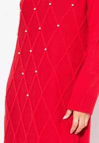 Rotes gestricktes Kleid mit Rautenmuster und Perlenverzierungen, mit gerippten Bündchen. Weiche Textur und figurbetontes Design.
