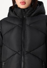 Black puffer jacket with a hood, featuring a zip front, diamond quilted design, and side pockets for added functionality.