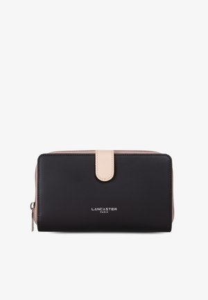 Portefeuille en cuir noir avec une texture lisse, un fermoir à pression beige et un logo de marque gravé en argent sur le devant. Fermeture zippée sur le côté.