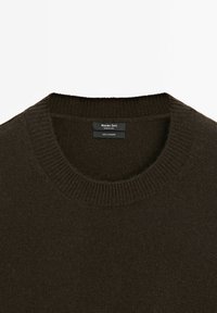 Maglione in cashmere marrone scuro con scollatura rotonda e rifiniture a coste sul colletto, sui polsini e sull'orlo. Etichetta con la scritta "100% Cashmere."
