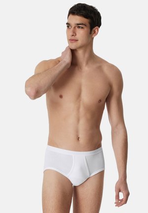 Culotte en coton blanc avec une texture côtelée et une taille élastique, présentant une poche frontale et un design ajusté. Idéal pour un usage quotidien.