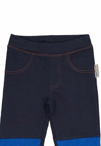 Marina blå byxor med orange sömmar, med framfickor och ett blått quiltat mönster vid fållen. Mjukt, elastiskt tyg.
