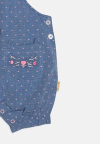 Blauer Stoff-Overall mit rosa Punkten, mit einem aufgestickten Katzenkopf auf der Tasche, elastischen Bündchen und Knopfdetails.