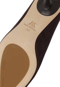 Ruskea mokkanahkakenkien pohja, jossa on kohokuvioitu logo, lause "AITO NAHKAA" ja koko "37." Pohjassa on sileä, vaaleanruskea viimeistely.