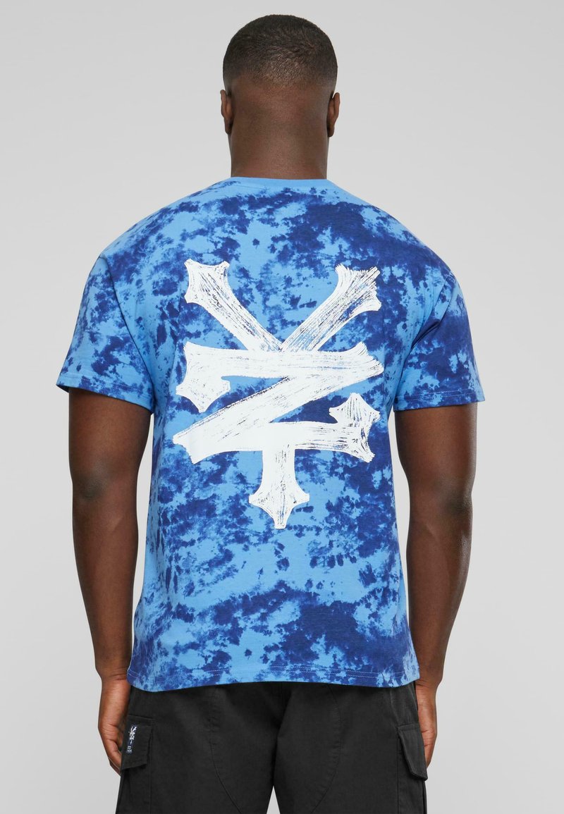 Blå tie-dye kortermet t-skjorte med et stort hvitt grafisk design på baksiden, med en avslappet passform og myk bomullstekstur.