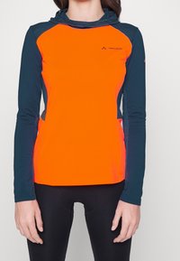 Långärmad träningsskjorta med en orange kropp och marinblå detaljer, med en hög halsdesign och en figurnära stil. Slät och lätt tyg.