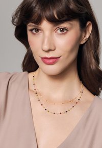 Złote naszyjniki z dwoma rzędami kolorowych koralików z różnych kamieni szlachetnych. Gładkie, delikatne łańcuszki uzupełniają projekt.