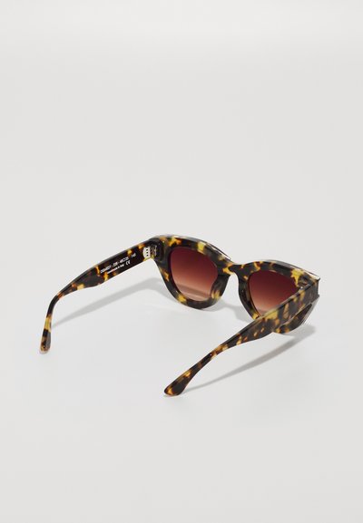 Tortoiseshell sunglasses with brown-tinted lenses, angular frames, and tapered arms. Features thin side temples and minimal branding.