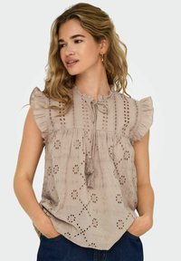 Helle beige Bluse mit rüschengesäumten kurzen Ärmeln, rundem Ausschnitt, dekorativer Stickerei und Bindeband an der Vorderseite. Lockerer Schnitt.