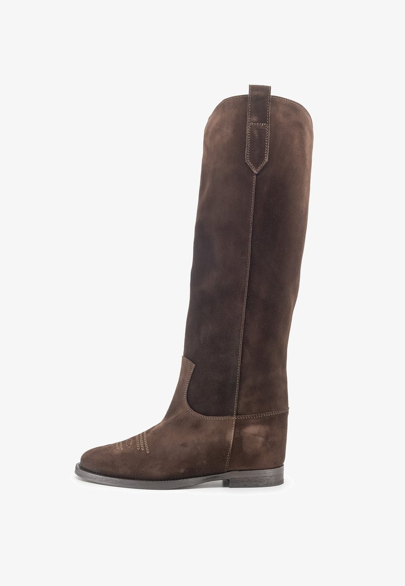 Stivale da cowboy alto in camoscio marrone scuro con dettagli di cuciture, linguetta per tirare sulla gamba e tacco basso in legno su sfondo bianco.