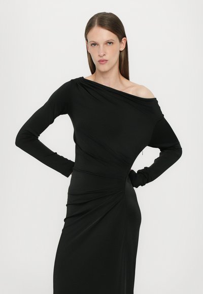 Black long-sleeve dress with an off-shoulder design, featuring draped, textured fabric and a twist detail at the waist.