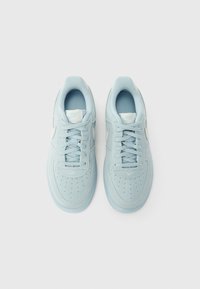 Svetlo moderni semišasti supergi okrogle oblike, s perforacijami, usklajenimi vezalkami in belim logotipom na strani.