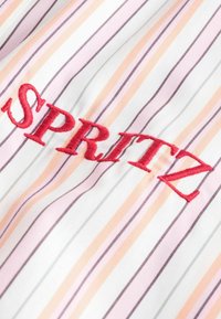 Tissu blanc avec des rayures verticales pêche, rose et grises, comportant un texte brodé rouge « SPRITZ » en lettres majuscules et grasses.