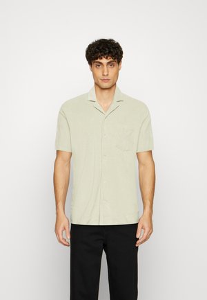 Korte mouwen, lichtgroen knoopshirt van zachte stof. Heeft een geknipte kraag en een opgestikte zak aan de linkerkant.