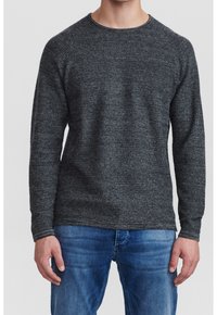 Mörkgrå stickad tröja med rund halsringning, texturerad tyg och långa ärmar, i kombination med ljusblå denimjeans.