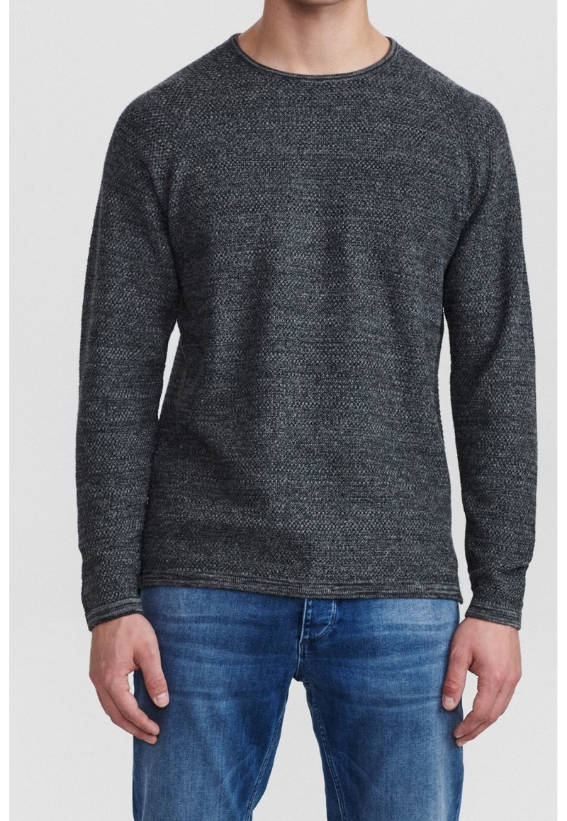 Mörkgrå stickad tröja med rund halsringning, texturerad tyg och långa ärmar, i kombination med ljusblå denimjeans.