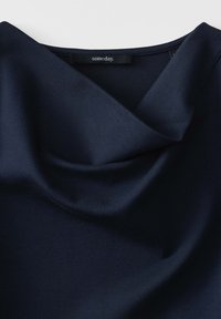Navy Cowl-Neck-Shirt aus glattem Stoff, mit einem drapierten Design und einem subtilen Glanz, sowie einem schwarzen Etikett mit der Aufschrift "irgendwann".