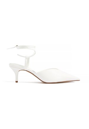 Witte kittenheel schoen met puntige neus, enkelbandje en slanke hak op witte achtergrond.