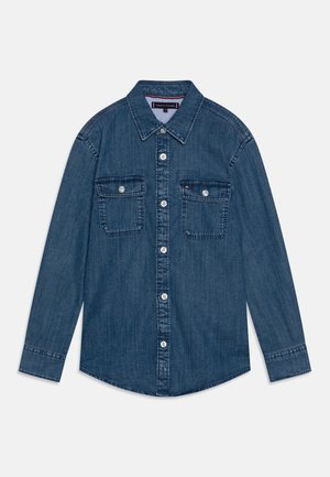 Langærmet blå denimskjorte med knapper foran, to knaplukningslommer på brystet og en krave, lagt fladt på en hvid baggrund.