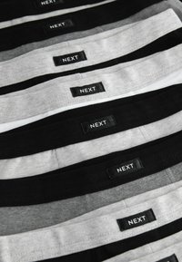 Set di underwear da uomo in diverse tonalità di nero, grigio e bianco. Ogni pezzo presenta un'etichetta con logo nero che recita "NEXT." Forma rettangolare.