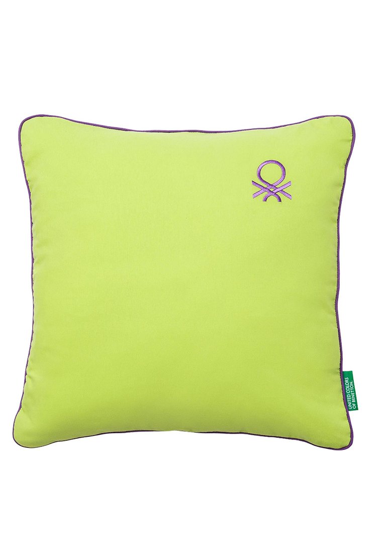 Coussin vert avec passepoil violet et logo brodé, forme carrée, texture lisse, détails de couture prononcés et étiquette sur le côté.