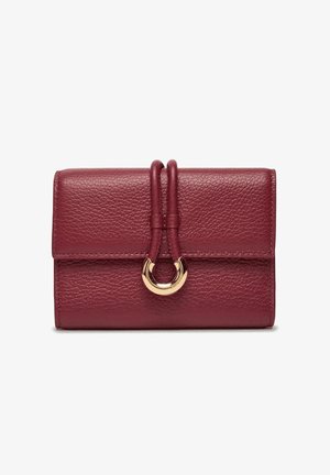 Portafoglio in pelle bordeaux con finitura testurizzata, caratterizzato da un accessorio circolare dorato e due cinturini intrecciati sul davanti.