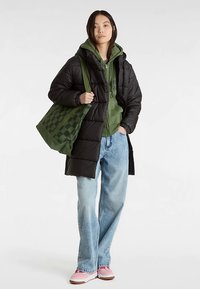 Zwarte donzen jas over een groene hoodie, lichtblauwe spijkerbroek en roze sneakers. Groene geruite draagtas. Soepele texturen, casual ontwerp.