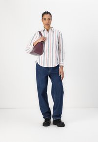 Raidoitettu button-up paita valkoisena, punaisena ja sinisenä; tummansiniset farkut; pitää pientä syvää violettia käsilaukkua; kengät, joissa on jykevät pohjat.