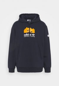 Námořnická mikina s kapucí, s oranžovým logem hory a bílým textem "adidas ADVENTURE", klokánkovou kapsou a ribovanými manžetami.