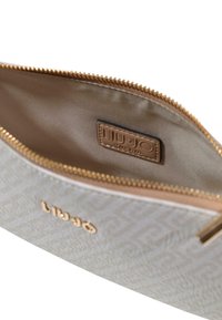 Borsellino Liu Jo in materiale grigio chiaro testurizzato con cerniera dorata. Interno con fodera beige e etichetta con logo per l'identificazione del marchio.