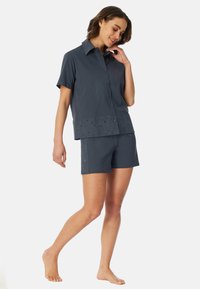 Mörkgrå bomullskortärmad skjorta med knappfront och broderad fåll, tillsammans med matchande shorts med dekorativa detaljer.
