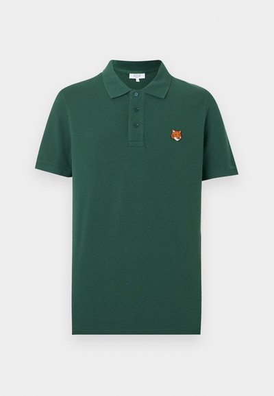 Polo vert foncé à manches courtes avec trois boutons et une petite tête de renard brodée sur le côté gauche de la poitrine.