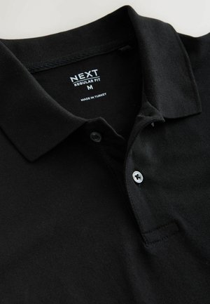 Schwarzes Poloshirt aus Baumwollstoff mit regulärer Passform, Zwei-Knopf-Leiste und Kragen. Verfügt über ein Etikett mit der Aufschrift "NEXT" und "Made in Turkey".