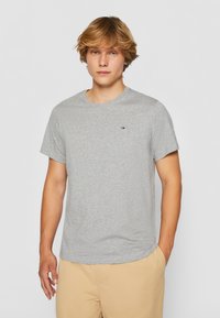 Grå bomullen t-shirt med korta ärmar och rundad hals. Har en liten logotyp på vänster bröstområde, slät textur och avslappnad passform.