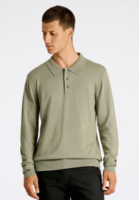 Polo a maniche lunghe in misto cotone verde tenue, con colletto classico, tre bottoni e polsini a coste. Tessuto liscio con un sottile motivo a maglia.
