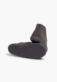 Bottines en daim gris foncé avec des semelles en caoutchouc texturé, présentant un design simple et des accents minimaux.