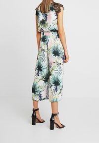 Kwiatowy kombinezon z dopasowanym w pasie, z zielonymi, różowymi i niebieskimi tropikalnymi wzorami. Czarne koronkowe akcenty na ramionach. Rozszerzane, krótkie nogawki.