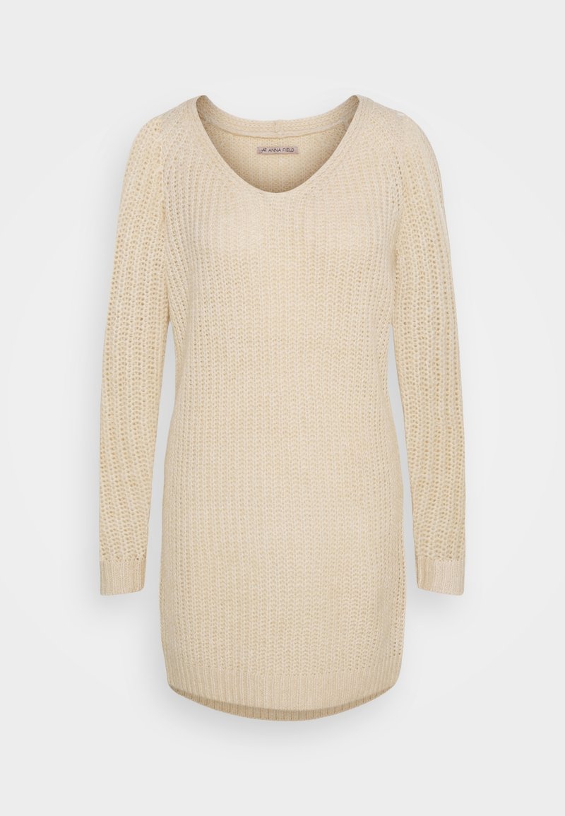 Maglione beige a maglia con scollo a V, maniche lunghe e polsini a costine; presenta una trama a trama larga e un orlo posteriore leggermente più lungo.