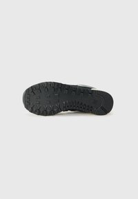 Semelle en caoutchouc noir avec un motif de crantage agressif, comportant des rainures et des crampons pour une adhérence optimale. Texture lisse, design fonctionnel pour une durabilité accrue.