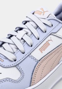 Puma lenkkarit valkoisena, vaaleansinisenä ja vaaleanpunaisena nahkana, joissa on tekstuuriset korostukset, näyttävä brändäys ja tasaiset nauhat.