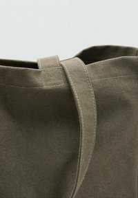 Borsa tote in tela verde con un design strutturato, caratterizzata da un'ampia apertura, dettagli di cuciture superiori e una maniglia robusta.