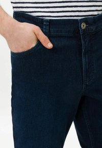 Donkerblauwe denim jeans met een slim fit, voorzien van een voorkant zak en een metalen knoop in de tailleband. Glad, lichtjes gestructureerde stof.