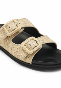 Sandale beige tissée à enfiler avec deux boucles réglables et semelle noire rembourrée, conçue pour un usage décontracté.