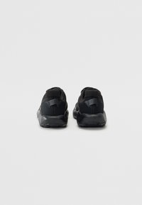 Sorte sportssko med mesh- og syntetisk overdel, polstret krave og gummi ydersål. Bagsiden har et minimalistisk design med diskret hardware.