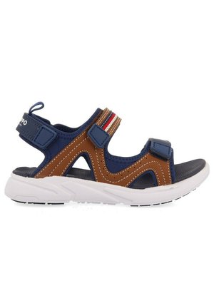 Sandalias deportivas azules y marrones con correas de Velcro, suela de goma blanca y diseño recortado. Presenta franjas de acento en rojo y blanco.