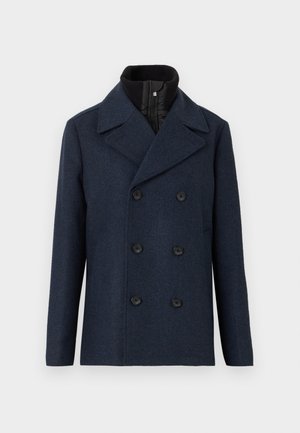 Cappotto in lana navy a doppio petto con grandi bottoni neri, revers a scelte e colletto interno con zip per un caldo supplementare e un contrasto di texture.