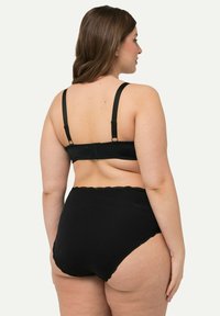 Set di biancheria intima nera composto da un bralette con spalline regolabili e chiusura a gancio, abbinato a slip a vita alta con dettagli in pizzo.