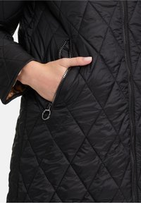 Zwarte gequiltte jas met diamantenpatroon, ritszakken aan de zijkant en een gladde textuur met een contrasterende voering.